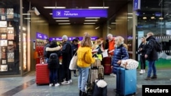 Travelers stand at the central station as Austria's rail workers stage a strike that shuts down all train traffic throughout the country after last minute pay negotiations fell through in Vienna, Austria, Nov. 28, 2022.