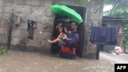 This handout photo taken on Dec. 25, 2022 and received on December 26 from the Philippine Coast Guard shows rescuers evacuating a child from a flooded area in Ozamiz City, Misamis Occidental.