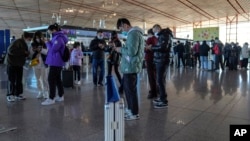 旅客在北京首都國際機場國際航班值機櫃檯辦理登機手續後使用智能手機填寫健康申明。（2022年12月29日，資料照片）