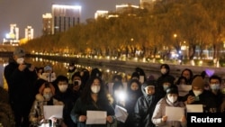 People in Beijing gather for a vigil and hold white sheets of paper on November 27, 2022, in protest over COVID-19 restrictions. (Thomas Peter/Reuters) 