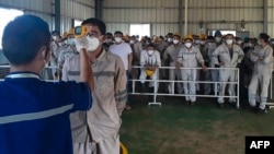 Petugas kesehatan memeriksa suhu tubuh pekerja PT Indonesia Morowali Industrial Park di Morowali, Sulawesi Tengah. (Foto: AFP)