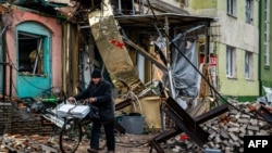 在頓涅茨克地區的巴赫穆特，一位當地居民推著自行車走過廢墟和阻擋坦克的障礙物。(2023年1月6日)