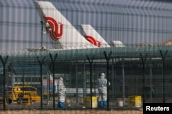 北京国际机场身穿防护服的工作人员站在中国航空公司的飞机附近。（2023年1月6日）