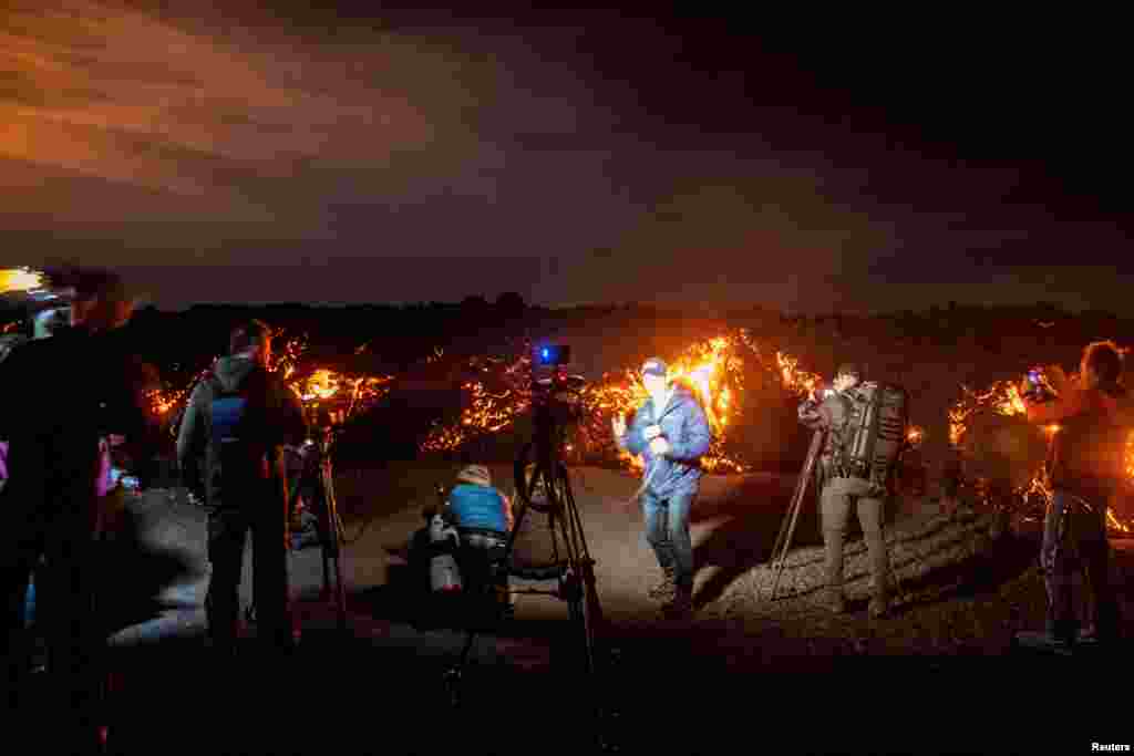 Members of the media report in front of a lava flow during the Mauna Loa volcano eruption in Hawaii, Nov. 30, 2022. 