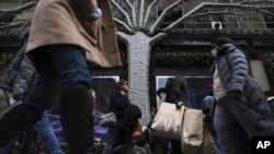 Compradores cargan bolsas en la Quinta Avenida, en Nueva York, el 25 de noviembre de 2022. (AP Foto/Julia Nikhinson)