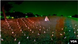 Aktivista sedi među zastavama postavljenim oko Vašingtonovog spomenika, u znak sećanja na Amerikance koji su izgubili život zbog pandemije koronavirusa. 