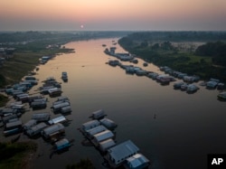 Surrounded by houses the lake in Carauari city is seen during sunrise, Amazonia, Brazil, Thursday, Sept. 1, 2022. Along the Jurua River, a tributary of the Amazon, riverine settlers and Indigenous villages are working together to promote the sustainable fishing of near magic fish called pirarucu. (AP Photo/Jorge Saenz)