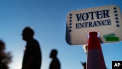 Voters pass a sign outside a polling site in Warwick, R.I., Nov. 7, 2022, after casting their ballots on the last day of early voting before the midterm election.