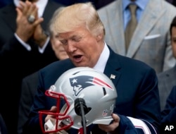 President Donald Trump is presented with a New England Patriots football helmet and jersey by Patriots coach Bill Belichick and Patriots owner Robert Kraft during a ceremony on the South Lawn of the White House in Washington, April 19, 2017.