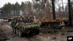 Soldados ucranianos captados el 31 de marzo mientras transitaban sobre vehículos blindados junto a un tanque ruso destruido en las afueras de Kiev. Alemania y otros países europeos refuerzan la ayuda al ejército del país invadido por Rusia.