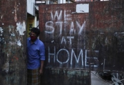 FILE - An Indian wearing a face mask looks out from a gate during lockdown to prevent the spread of new coronavirus in Hyderabad, India, April 18, 2020.