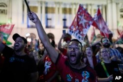 Followers of former Brazilian President Luiz Inacio Lula da Silva, who is running for president again, react to partial results after general election polls closed in Rio de Janeiro, Brazil, Sunday, Oct. 2, 2022. (AP Photo/Silvia Izquierdo)