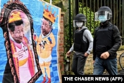 中国驻曼彻斯特领事馆工作人员走向领馆外由反中共二十大示威者竖立的中国领导人习近平的漫画。（2022年10月16日）