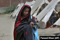 Flood victim Rajul Noor walks towards her tent school at a relief camp, in Dadu district, Pakistan, Sept. 23, 2022. (AP Photo/Fareed Khan)