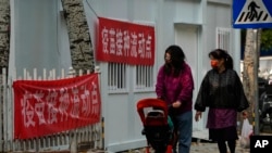 資料照：帶著口罩推著嬰兒車的女子走過北京的一處疫苗接種流動點。 （2022年10月26日）