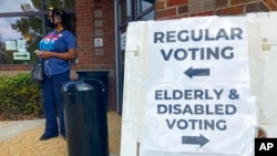 FILE - Signs showing the way for voters stand outside a Cobb County voting building during the first day of early voting, Oct. 17, 2022, in Marietta, Ga.