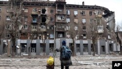 A local resident looks at a damaged during a heavy fighting apartment building in an area controlled by Russian-backed separatist forces in Mariupol, Ukraine, April 16, 2022.