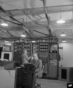 Inženjeri zvuka Alton Miler i Fred Laouet instaliraju radijski studio u novoj zgradi Glasa Amerike u centru Vašingtona, gde se medij preselio iz Njujorka 1954. godine.