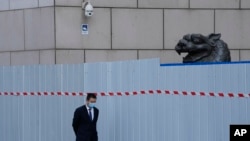 上海一家商場圍欄外走過一名戴著口罩的工作人員。（2022年4月20日）