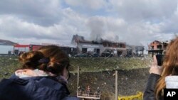 Watu wanapiga picha jumba lenye shughuli za biashara lililoharibiwa na makombora ya Russia mjini Lviv, Ukraine