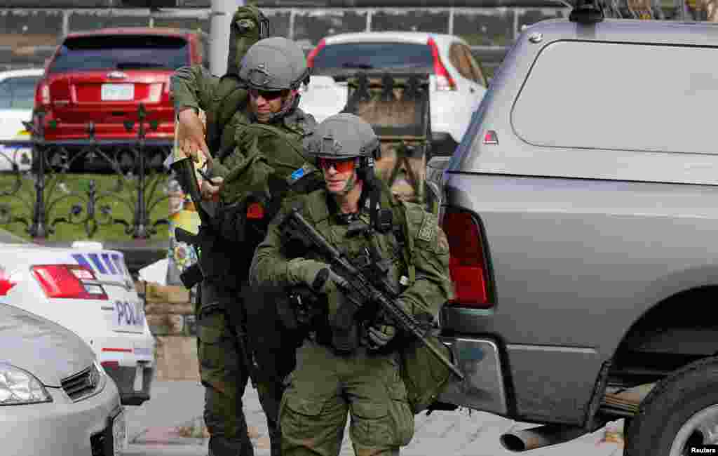 Armed RCMP officers approach Parliament Hill following a shooting incident. 