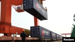 资料照：中国浙江省义乌火车站的一名工人在给开往欧洲的火车上装载集装箱。（2017年4月15日）