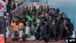 資料照片: 2023年10月12日移民在西班牙下船後坐在地上