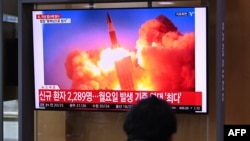 People watch a television news broadcast showing file footage of a North Korean missile test, at a railway station in Seoul on September 28, 2021, after North Korea fired an "unidentified projectile" into the sea off its east coast, according to the South