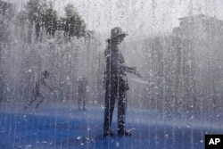 زنی در یک پارک فواره در لندن سعی دارد خنک شود