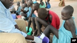 FILE - Ajak Kuol Nyamchiek watches while John Lotiki, a nurse with the Carter Center, bandages blisters on her leg from where a Guinea worm is emerging, Abuyong, Sudan, Nov. 4, 2010.