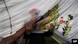 Un oficial de policía sostiene la bandera nacional mexicana mientras se iza en el Aeropuerto Internacional Benito Juárez en la Ciudad de México, el miércoles 25 de marzo de 2020.