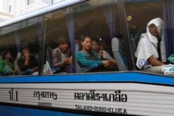 FILE: Cambodian migrant workers sit in a bus upon arrival at Cambodia-Thailand's international border gate in Poipet, Cambodia, from Thailand, Tuesday, June 17, 2014.