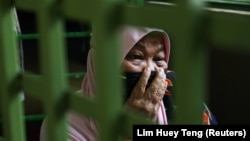 Halijah Naemat, 74, cries while members of public come over to help after she hung a white flag outside her home during an enhanced lockdown, amid the coronavirus disease (COVID-19) outbreak, in Petaling Jaya, Malaysia July 6, 2021. (REUTERS/Lim Huey Teng)