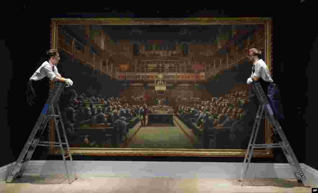 Sotheby's employees look at a painting by anonymous street artist Banksy on display at Sotheby's auction rooms in London.