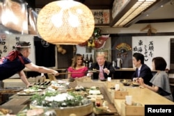 El presidente de EE.UU., Donald Trump, con la primera dama Melania Trump, recibe un plato con comida de un chef durante una cena con el primer ministro de Japón Shinzo Abe y su esposa Akie Abe en Tokio. Mayo 26 de 2019.