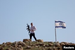 مغربی کنارے میں اسرائیلی فوجی چوکی کے قریب دیکھا جانے والا ایک مسلح شخص۔ 4 فروری 2024