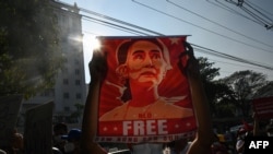 FILE - In this file photo taken on Feb. 15, 2021, a protester holds up a poster featuring Aung San Suu Kyi during a demonstration against the military coup at in front of the Central Bank of Myanmar in Yangon.