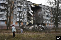 A woman passes by an apartment building damaged following by Russian shelling in Bakhmut, the site of the heaviest battles with the Russian troops, in the Donetsk region, Ukraine, Sunday, Dec. 11, 2022. (AP Photo/Andriy Andriyenko, File)