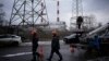 ARCHIVO - Trabajadores de servicios públicos caminan junto a una planta de energía después de un ataque con misiles en Kiev, Ucrania, el 26 de enero de 2023.