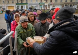 Local residents stand in line waiting for free bread from volunteers in Bakhmut, the site of the heaviest battle against the Russian troops in the Donetsk region, Ukraine, Friday, Oct. 28, 2022. (AP Photo/Efrem Lukatsky, File)