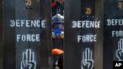  2021年3月11日，一名反政變抗議者從緬甸仰光設立的臨時路障空隙中窺視。（美聯社照片）