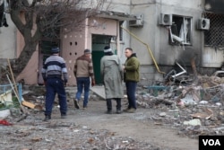 Los hombres ingresan a un edificio casi destruido para buscar alguna de sus pertenencias que aún estén intactas, en Borodyanka, Ucrania, el 6 de abril de 2022. [Heather Murdock/VOA]