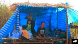 FILE - Displaced people from Myanmar live under a makeshift tent along the Thai side of the Moei River in Mae Sot, Thailand, Feb. 7, 2022. 