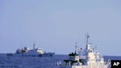 In this photo provided by the Philippine Coast Guard, a Chinese Coast Guard ship sails near a Philippine Coast Guard vessel during its patrol at Bajo de Masinloc, 124 nautical miles west of Zambales province, northwestern Philippines on March 2, 2022.