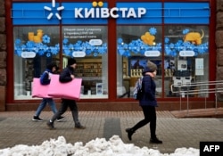 Orang-orang berjalan melewati toko Kyivstar, sebuah perusahaan telekomunikasi Ukraina, di Kyiv pada 12 Desember 2023. (Foto: AFP)