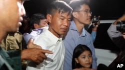 FILE - Two former Radio Free Asia reporters Uon Chhin, center, and Yeang Socheamet, right, hold together as they walk outside the main prison of Prey Sar at the outskirt of Phnom Penh, Cambodia, Aug. 21, 2018.