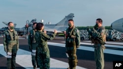 ARCHIVO - En esta foto de archivo del 15 de septiembre de 2021 publicada por la Oficina Presidencial de Taiwán, la presidenta taiwanesa Tsai Ing-wen, centro, habla con personal militar cerca de un avión estacionado en una carretera en Jiadong, Taiwán.
