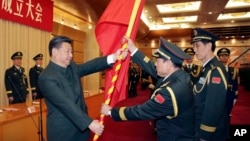 中共領導人習近平在北京舉行的中國人民解放軍戰區成立大會上向火箭軍將領、中國防長魏鳳和（中）授予軍旗。（資料圖片）