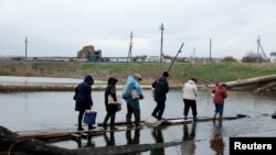 Las personas regresan a sus refugios mientras cruzan un puente destruido después de recolectar ayuda, mientras continúa la invasión de Ucrania por parte de Rusia, en la región oriental de Donbas en Bakhmut, Ucrania, el 30 de octubre de 2022.