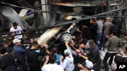 This photo released by the Syrian official news agency SANA shows Syrians pushing a car at the scene after a blast in Damascus, Syria, November 5, 2012. 